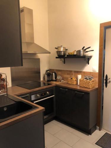 une cuisine avec des armoires noires, des casseroles et des poêles sur une étagère dans l'établissement Boulogne-sur-Mer : très bel appartement de charme, à Boulogne-sur-Mer