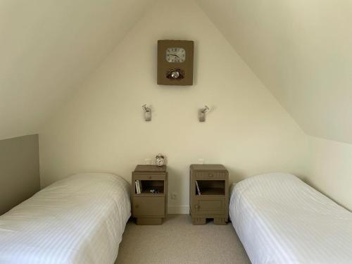 a bedroom with two beds and a clock on the wall at Fleur & Mer in Montfarville