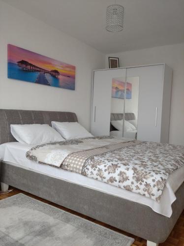 a bedroom with a large bed with a large painting on the wall at Apartman Nova Varos in Banja Luka