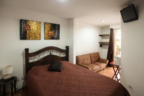 - une chambre avec un lit et un canapé dans l'établissement Melrost Airport Bed & Breakfast, à Alajuela