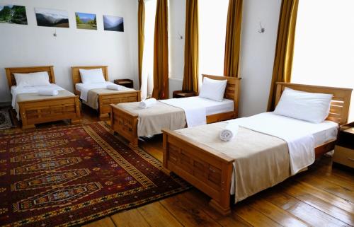 a room with three beds and a rug at Nazy's Guest House in Joqolo