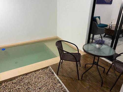 a room with a glass table and two chairs and a table and a table at New & beautiful apartment GF with private pool in Mérida