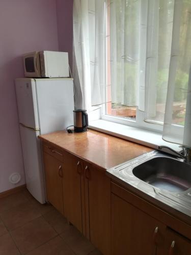 a kitchen with a white refrigerator and a window at Oāze Smiltenē in Smiltene