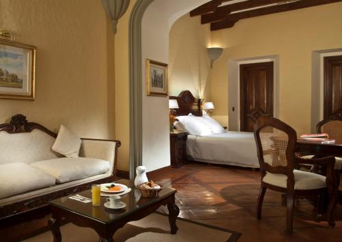 Una sala de estar con un sofá, una mesa y una cama. en Fiesta Americana Hacienda San Antonio El Puente Resort & Spa, en Cuernavaca