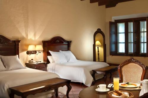 Una habitación de hotel con dos camas y una mesa y sillas. en Fiesta Americana Hacienda San Antonio El Puente Resort & Spa, en Cuernavaca