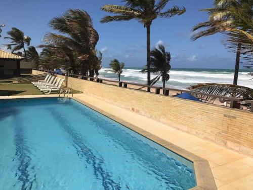 a swimming pool with the beach in the background at Beira Mar Salvador Bahia Brazil climatizado in Salvador
