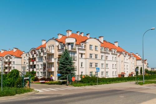 un grand bâtiment blanc avec des toits rouges dans une rue dans l'établissement Belweder Diamentowy, à Olsztyn