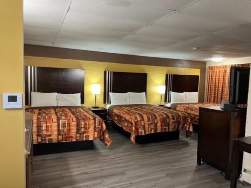a hotel room with two beds and a flat screen tv at Scottish Inns Tonawanda in Tonawanda