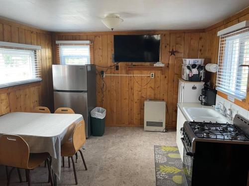 cocina con mesa, fogones y nevera en Cozy cabin #1 at Aspen Ridge Cabins, en South Fork