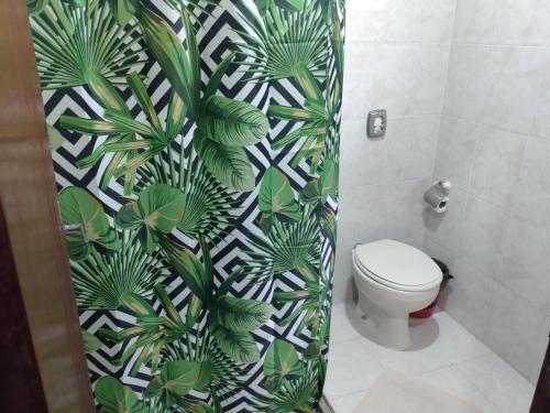 a bathroom with a toilet and a green and white wallpaper at Pousada Sol e Verão in São Pedro da Aldeia