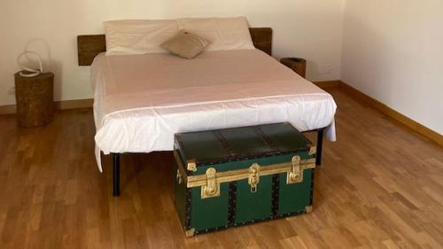 ein Bett mit grünem Kofferraum darüber in der Unterkunft Ex Villa Gastaldi in Asti