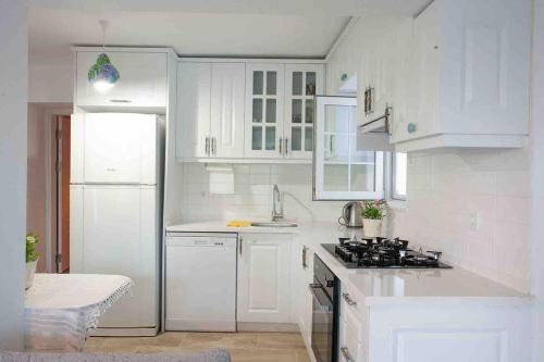 a white kitchen with a stove and white cabinets at Mor Salkım Evi in Datca
