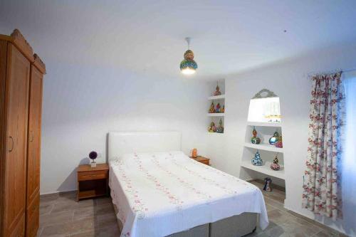 a bedroom with a white bed and a window at Mor Salkım Evi in Datca