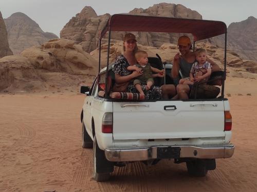 rodzina siedząca z tyłu ciężarówki na pustyni w obiekcie Traditions of Wadi Rum camp & jeep tour w mieście Wadi Rum