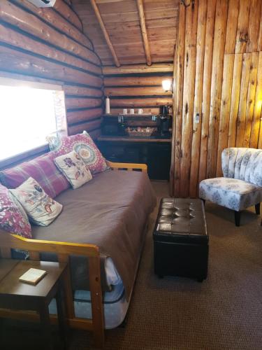 a bedroom with a bed and a chair in a log cabin at Yellowstone Hot Springs Resort in Gardiner