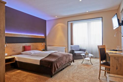 a bedroom with a bed and a desk and a chair at Hotel & Restaurant Zum Karpfen in Obernburg am Main