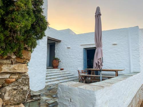 Sympopoula House في Sifnos: فناء فيه مظلة وطاولة وكراسي