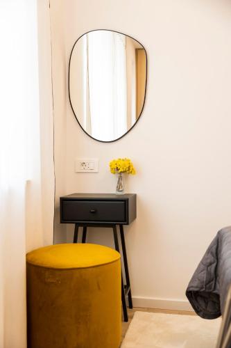 a mirror on a wall next to a table with a yellow stool at Sidra city apartment in Zadar