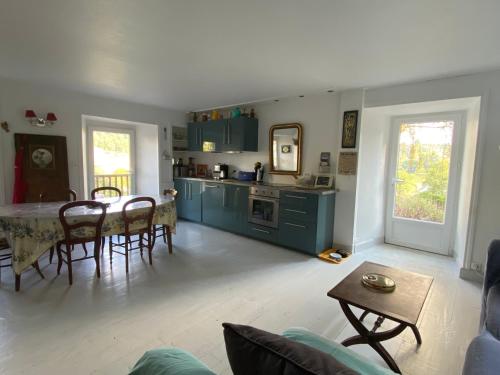 un salon avec une table et une cuisine dans l'établissement Maison de village avec terrasse et jardin Saint Urcize, à Saint-Urcize