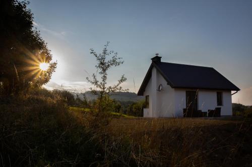 a small white house with the sun in the sky at DOMEK NA WIERCHACH in Piwniczna