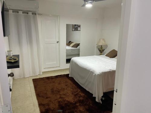 biała sypialnia z łóżkiem i lustrem w obiekcie Hospedaje de marant 2 w mieście Puerto Plata