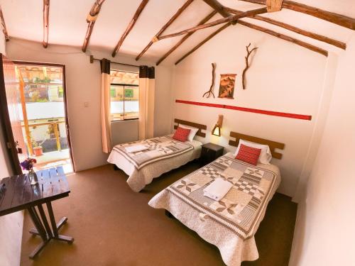 a room with two beds and a table and a window at La Casa de la Abuela Isabel in Yanque