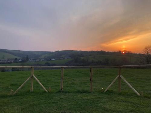 a fence in a field with a sunset in the background at Eden House 1-bedroom, horses welcome. in Whitland