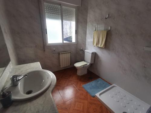 uma casa de banho com um lavatório e um WC em Morriña & Wanderlust - Alojamiento 1 em Meaño