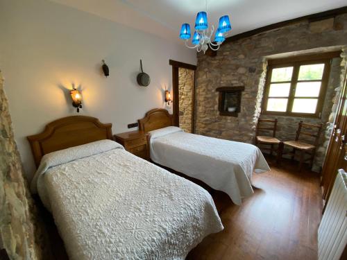 a bedroom with two beds and a stone wall at Casa Rural Iratxeko-Berea in Bera