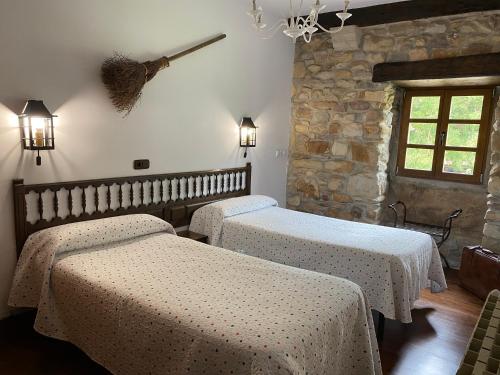 a bedroom with two beds and a stone wall at Casa Rural Iratxeko-Berea in Bera