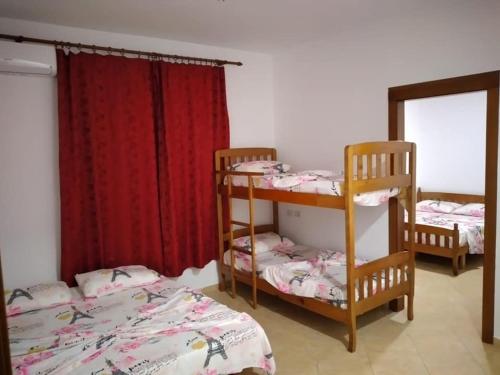 2 Etagenbetten in einem Zimmer mit roten Vorhängen in der Unterkunft Doçi Hotel in Velipojë