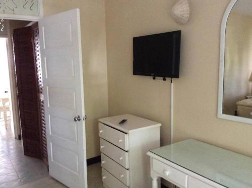 a room with a refrigerator and a television on the wall at Lush Tropical apartment located in a 4-star resort in Runaway Bay