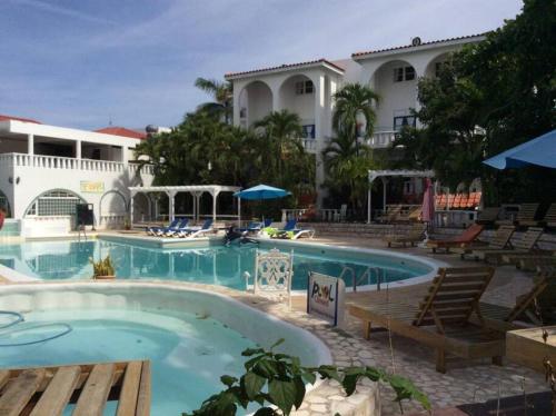 una piscina en un complejo con sillas y un edificio en Lush Tropical apartment located in a 4-star resort en Runaway Bay