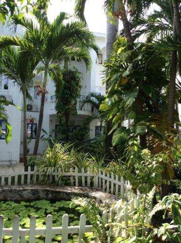 a white fence in front of a garden with palm trees at Lush Tropical apartment located in a 4-star resort in Runaway Bay