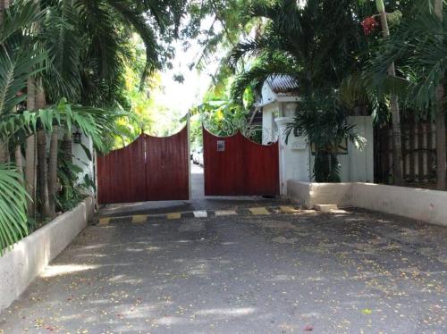a red gate in front of a house with palm trees at Lush Tropical apartment located in a 4-star resort in Runaway Bay