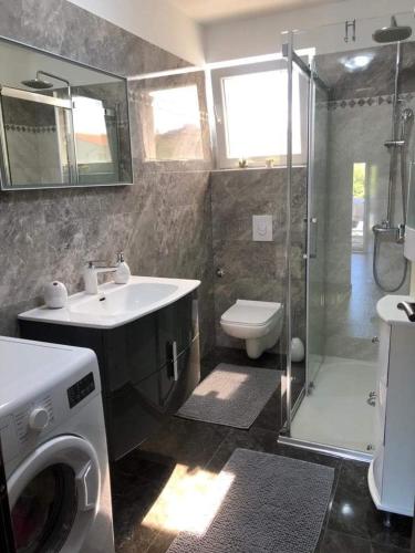 a bathroom with a sink and a washing machine at Apartament Maja in Rogoznica