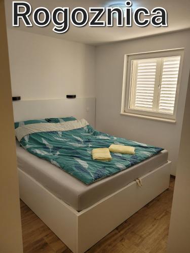a bedroom with a bed in a room with a window at Apartament Maja in Rogoznica