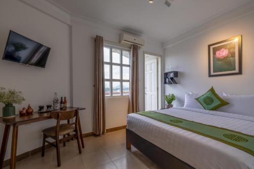 a bedroom with a bed and a desk and a window at Purple Hue - Charming Riverside in Hue