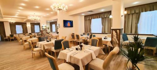 a restaurant with white tables and chairs and windows at ApartHotel Olympus Plaza in Kranevo