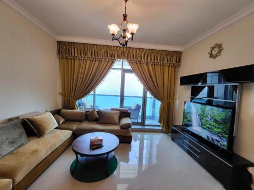 a living room with a couch and a television at Beachfront Holiday Homes in Ajman 