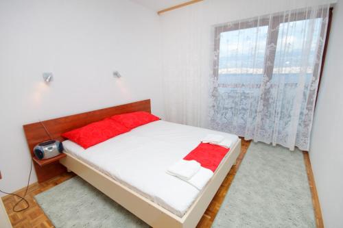 Schlafzimmer mit einem Bett mit roten Kissen und einem Fenster in der Unterkunft Apartments with a parking space Bosana, Pag - 9374 in Pag