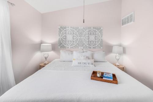 a white bedroom with a large white bed with a tray on it at Oceanside Retreat in Corpus Christi