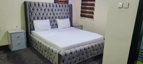un letto con testiera imbottita in una stanza di Prince's - Villa - Minimum of 3 nights booking ad Akure