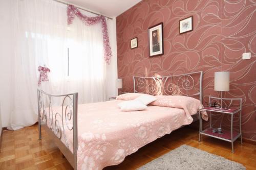 a bedroom with a bed and a red wall at Apartments by the sea Slatine, Ciovo - 9454 in Slatine