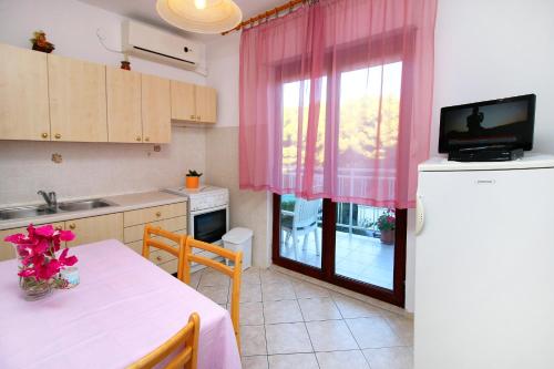 a kitchen with a table and a window with pink curtains at Apartment Bilo 9467d in Zaboric