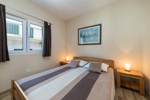 una camera da letto con un grande letto con due finestre di Apartments by the sea Drvenik Donja vala, Makarska - 9654 a Drvenik