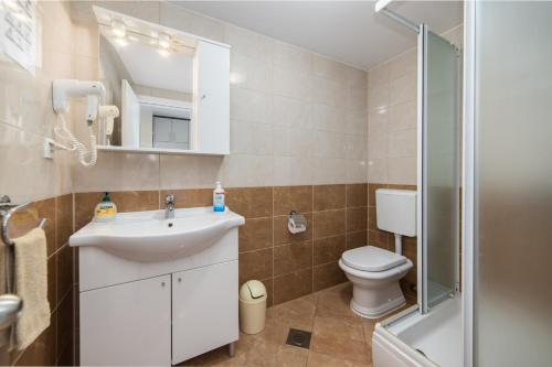 a bathroom with a sink and a toilet and a mirror at Apartments by the sea Drvenik Donja vala, Makarska - 9654 in Drvenik