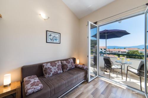 a living room with a couch and a balcony with an umbrella at Apartments by the sea Drvenik Donja vala, Makarska - 9654 in Drvenik