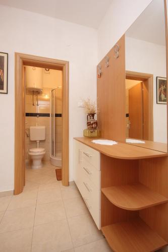 a bathroom with a sink and a toilet and a mirror at Apartment Dinjiska 9386a in Povljana