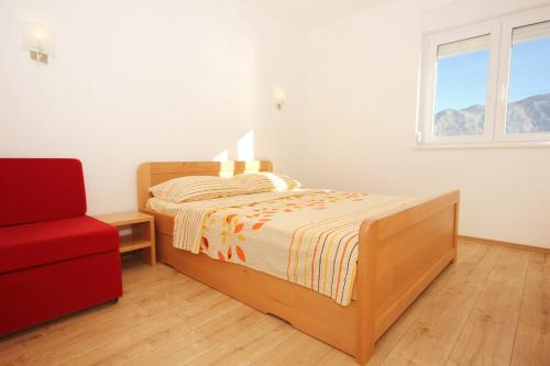 um quarto com uma cama e uma cadeira vermelha em Apartment Duce 9437g em Dugi Rat